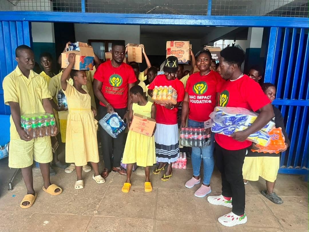 RAC Impact Foundation volunteers in red shirts with pupils and donated supplies